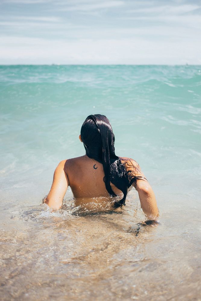 A young black haired caucasian woman swims in the ocean