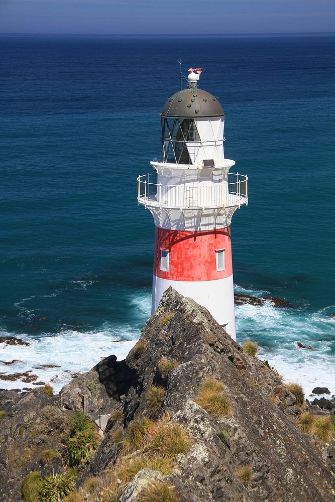 Lighthouse on a cliff near seashore. Free public domain CC0 photo.
