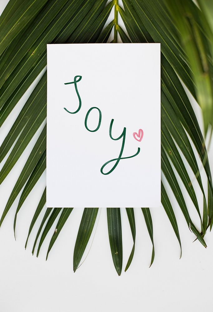 Card with a text Joy in tropical background
