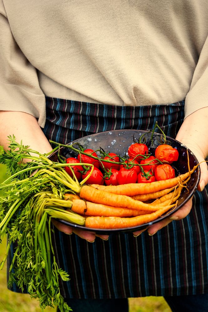 Woman holding a plate of carrots and tomatoes