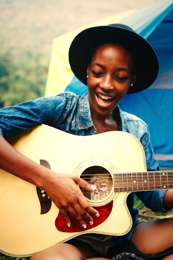 Woman playing guitar at a campsite
