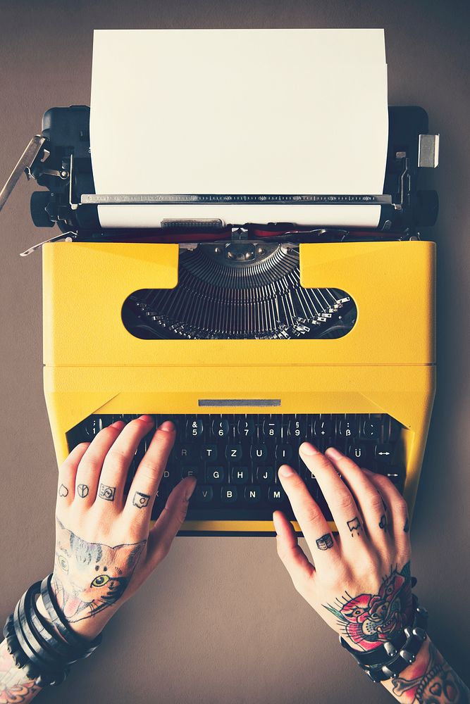 Tattooed woman typing on a vintage typewriter