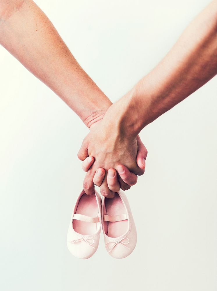 Couple holding a pair of baby girl shoes