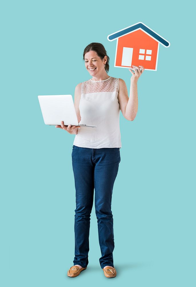 Woman holding a house icon and using a laptop