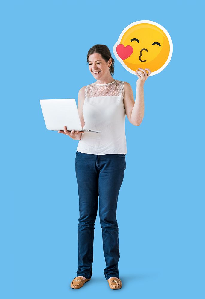 Woman holding a kissing emoticon and a laptop