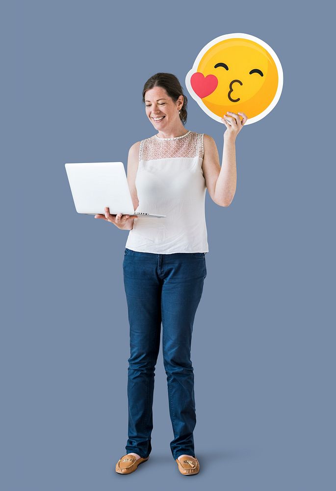 Woman holding a kissing emoticon and a laptop