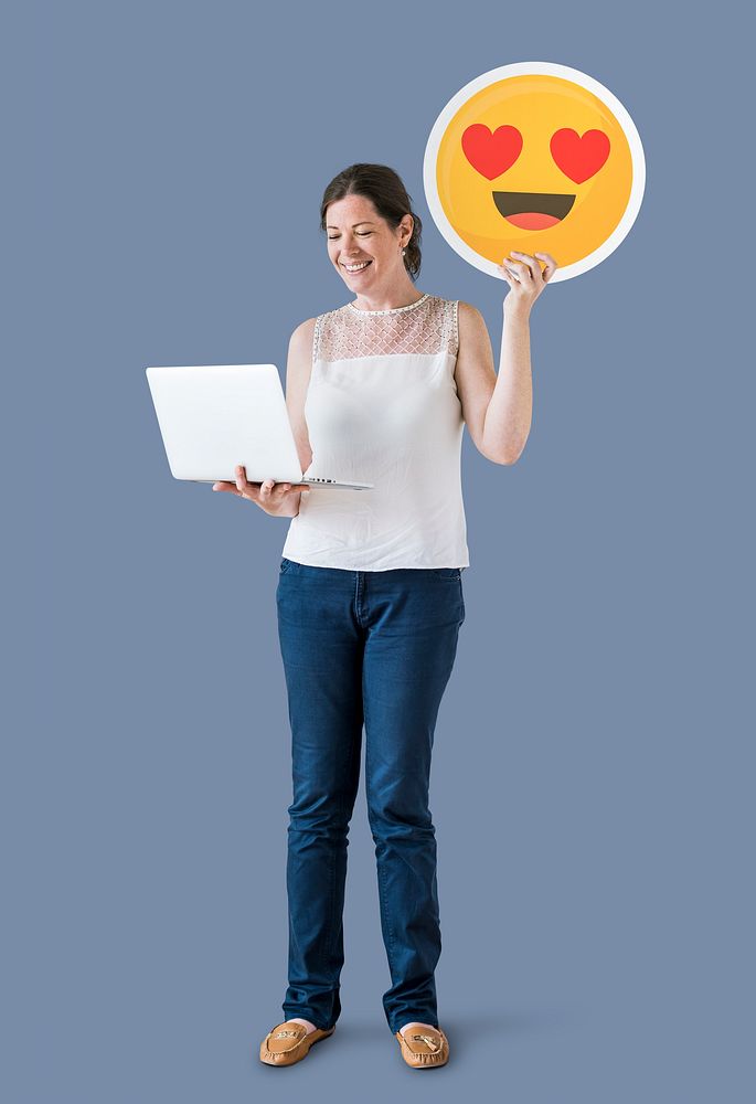 Woman holding a heart eyes emoticon and a laptop