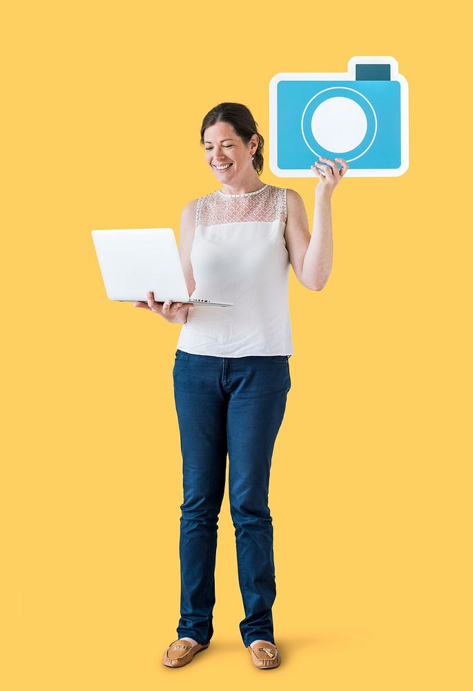 Woman holding a camera icon and using a laptop