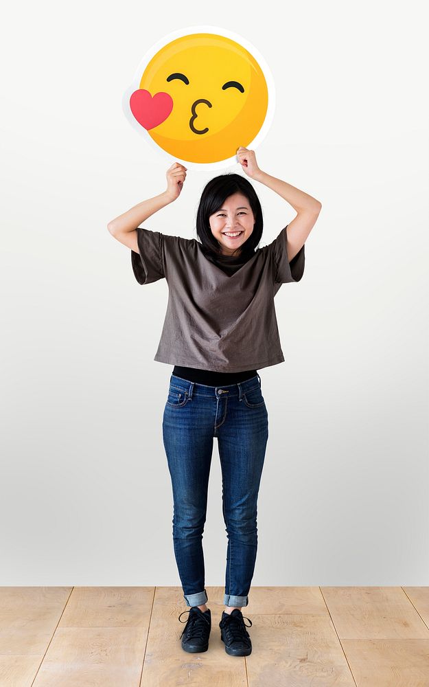 Cheerful woman holding a kissing emoticon