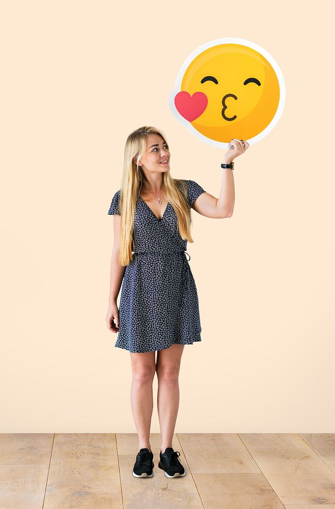 Cheerful woman holding a kissing emoticon
