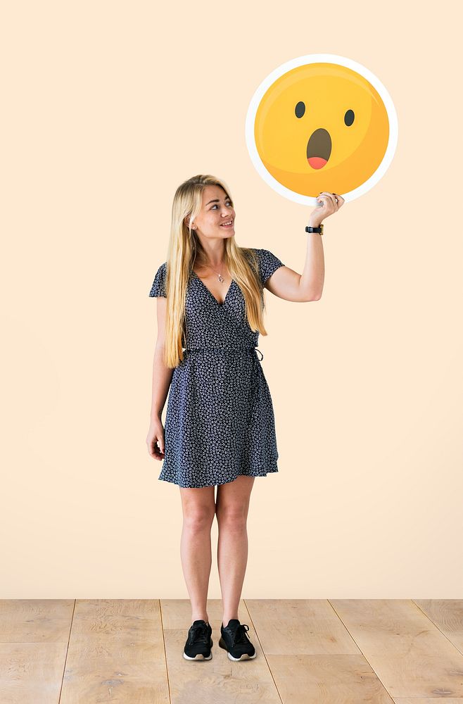 Cheerful woman holding a surprised emoticon