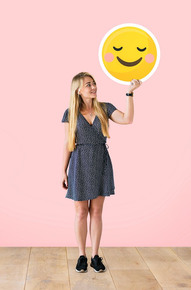 Cheerful woman holding a blushing emoticon