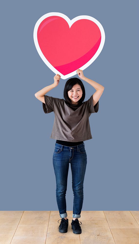 Woman holding a heart emoticon in a studio