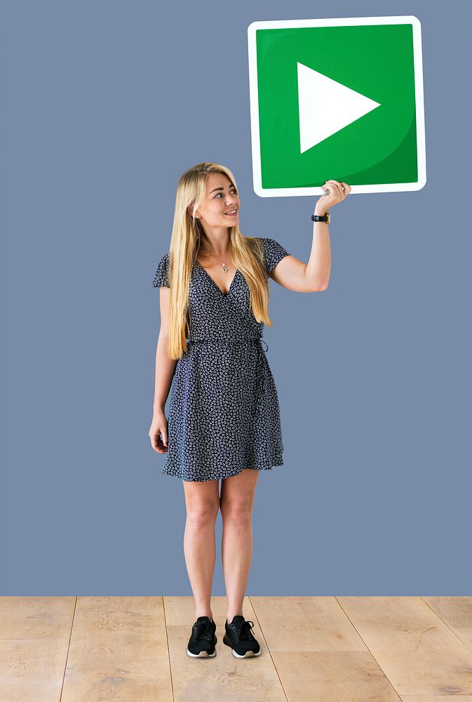 Woman holding a play button icon in a studio