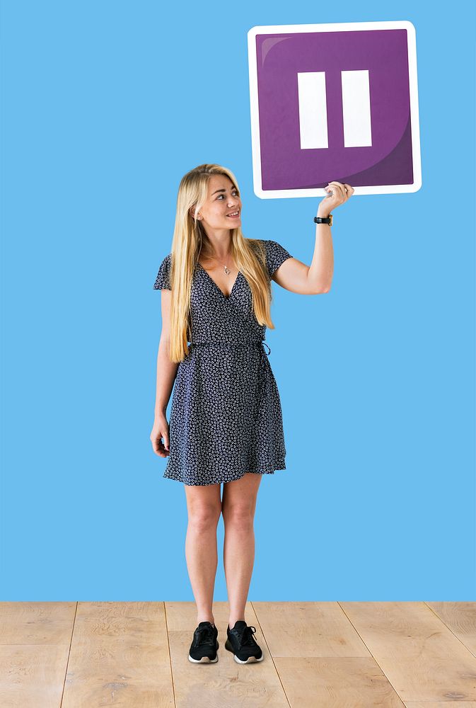 Woman holding a pause button icon in a studio