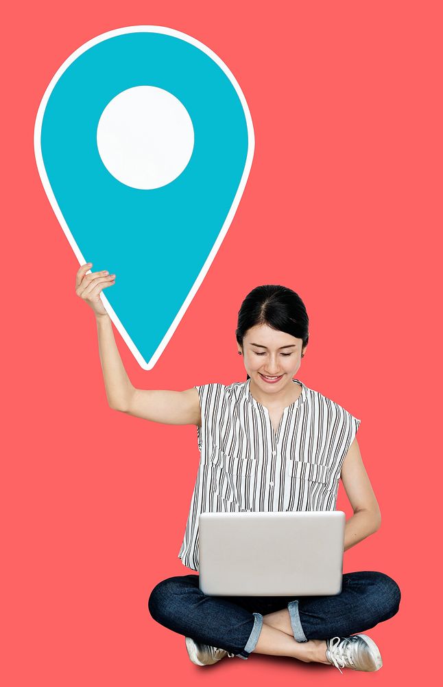 Woman using a laptop and holding a location pin