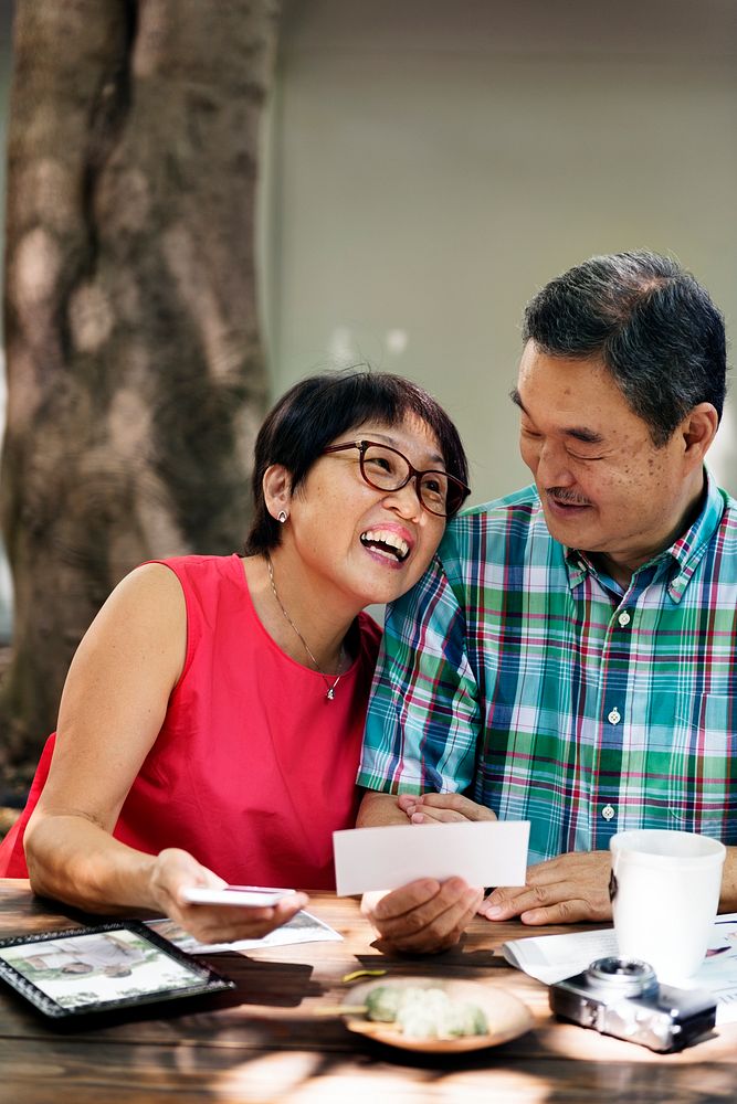 Senior Asian Couple Smiling Reminiscing Phographs Concept