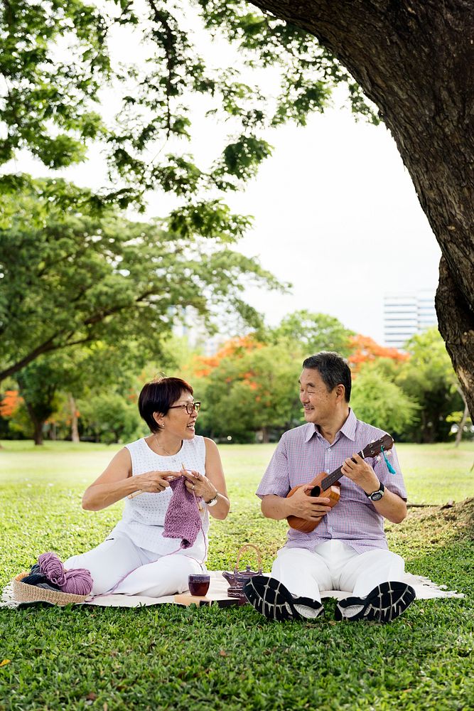 Senior Asian couple playing music in a park