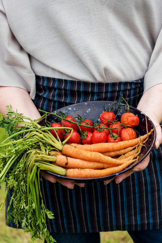 Woman holding a plate of carrots and tomatoes
