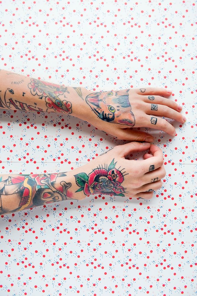 Tattooed arms on red dots background