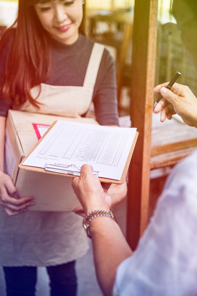 Young woman receive a parcel and sign the document