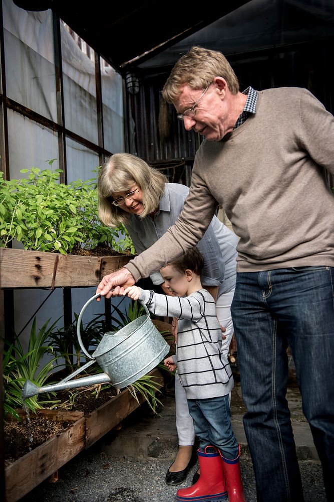 Grandparents helping a young boy water the plants