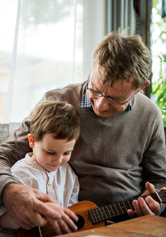 Grandfather teaching grandson how to play ukelele