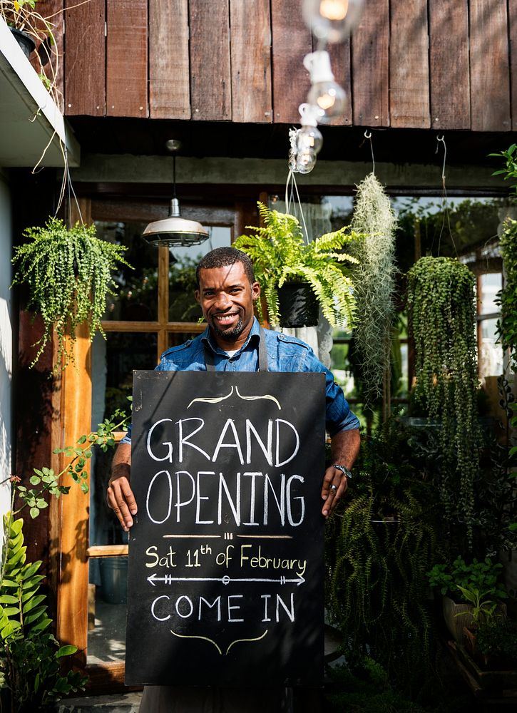 African Dscent Man Carrying Shop Grand Opening Board Announcement