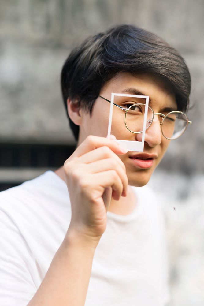 Young asian man holding photograph cover his eye
