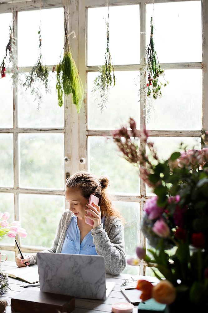 Woman talking on the phone with plants hanging above