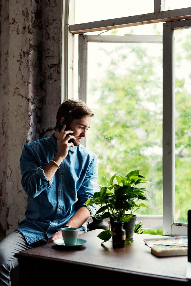 Man sitting near the window and using the phone