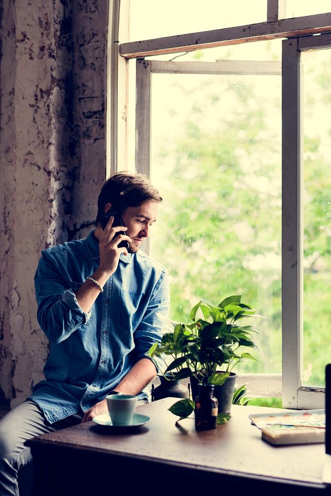 Man sitting near the window and using the phone