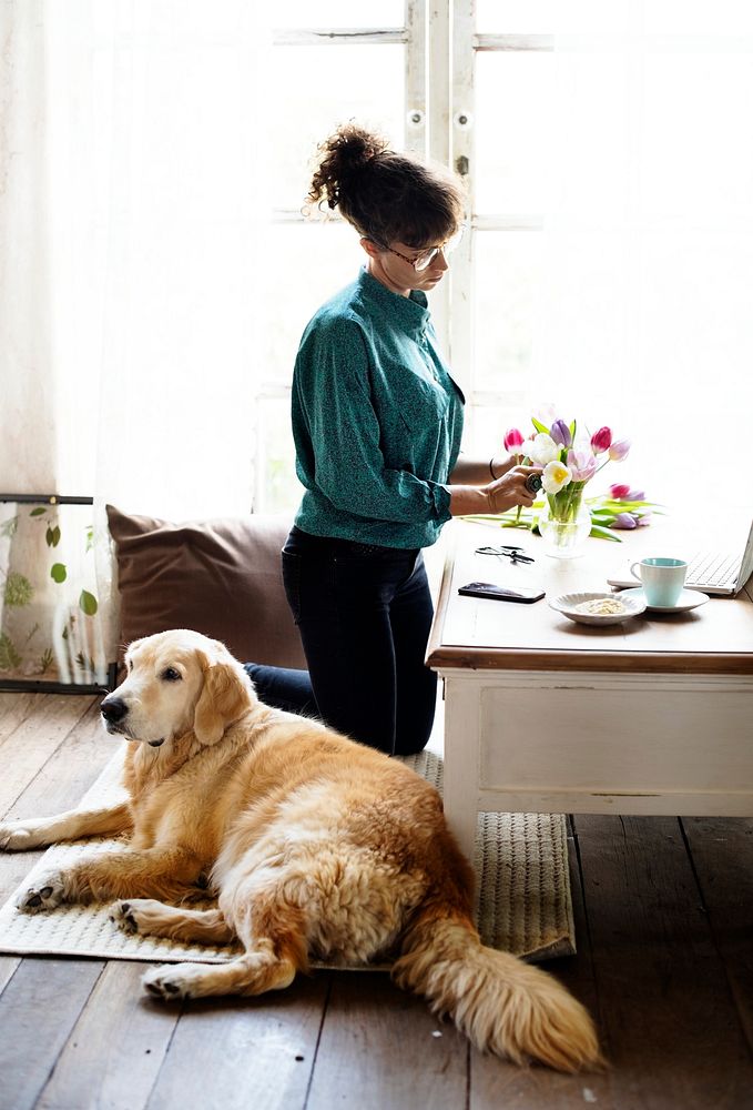 Woman Arranging Flowers with Goldent Retriever Dog Laying