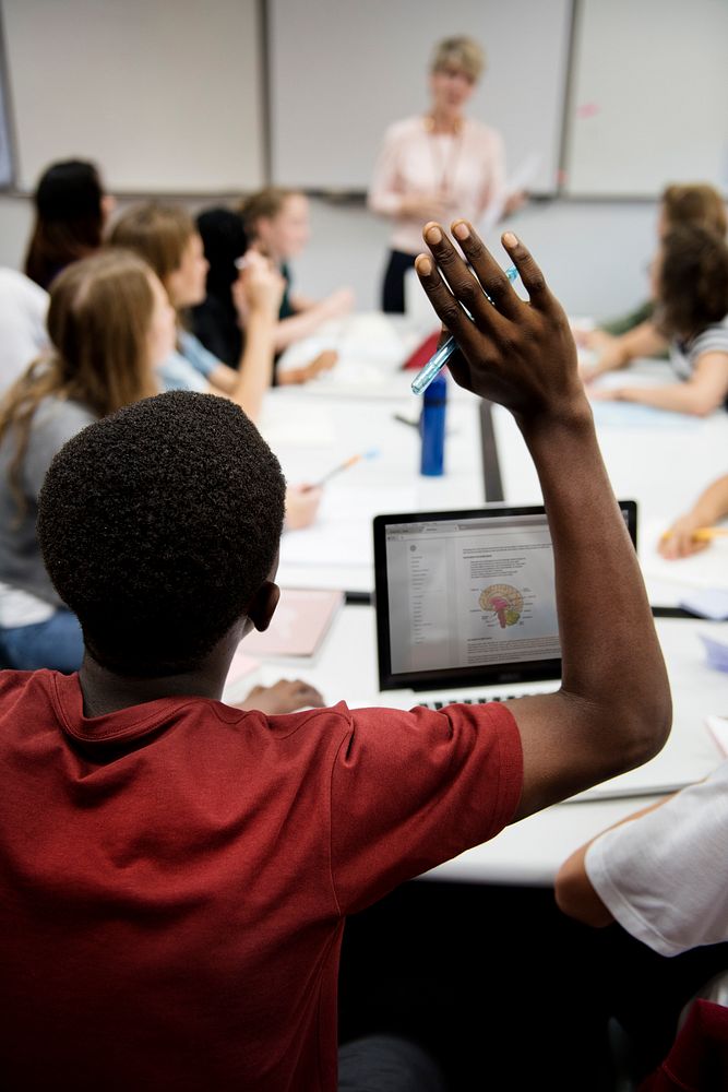 High school student rasing arm in classroom