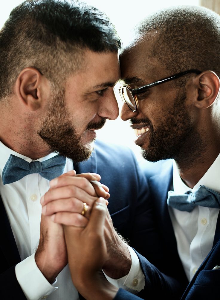 Closeup of gay couple smiling holding hands together