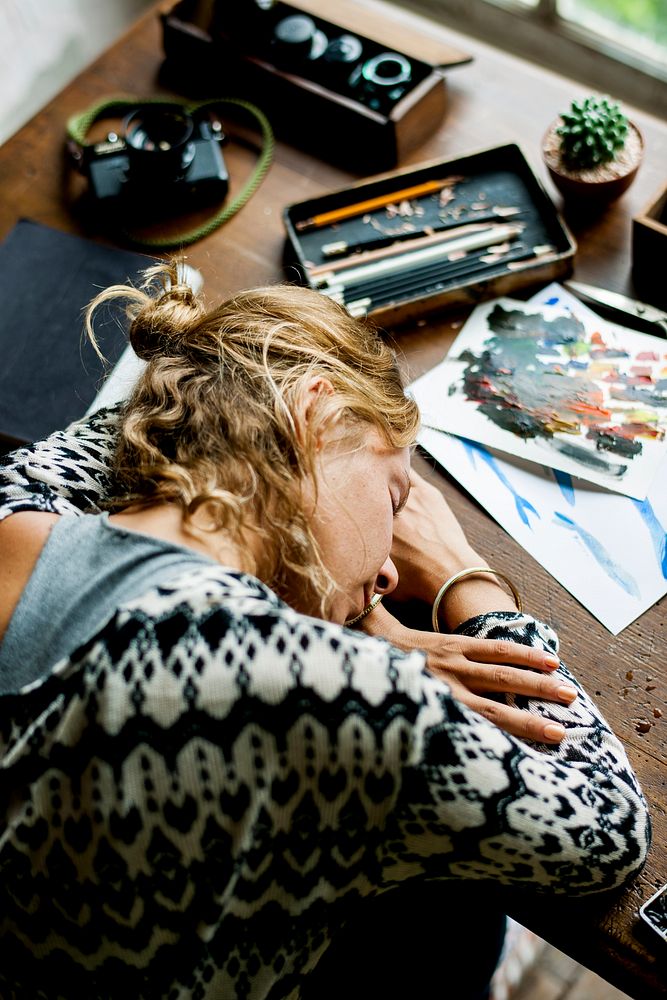 Rear view of artist woman taking a nap on work table