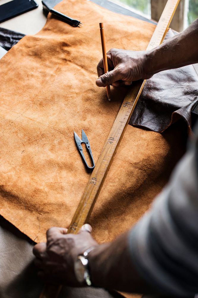 Closeup of craftsman measuring leather handicraft