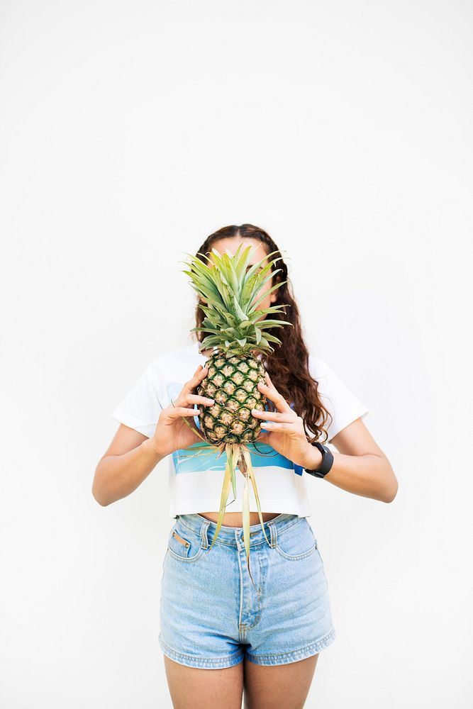 Asian woman holding pineapple covering face