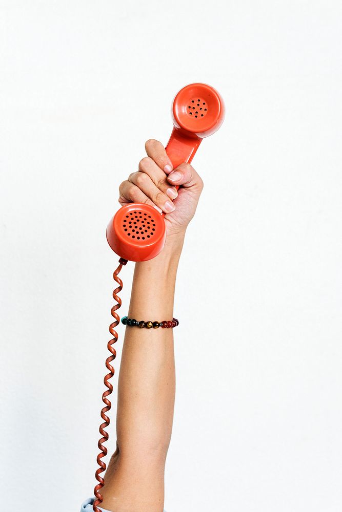 Hand holding red retro telephone isolated on white