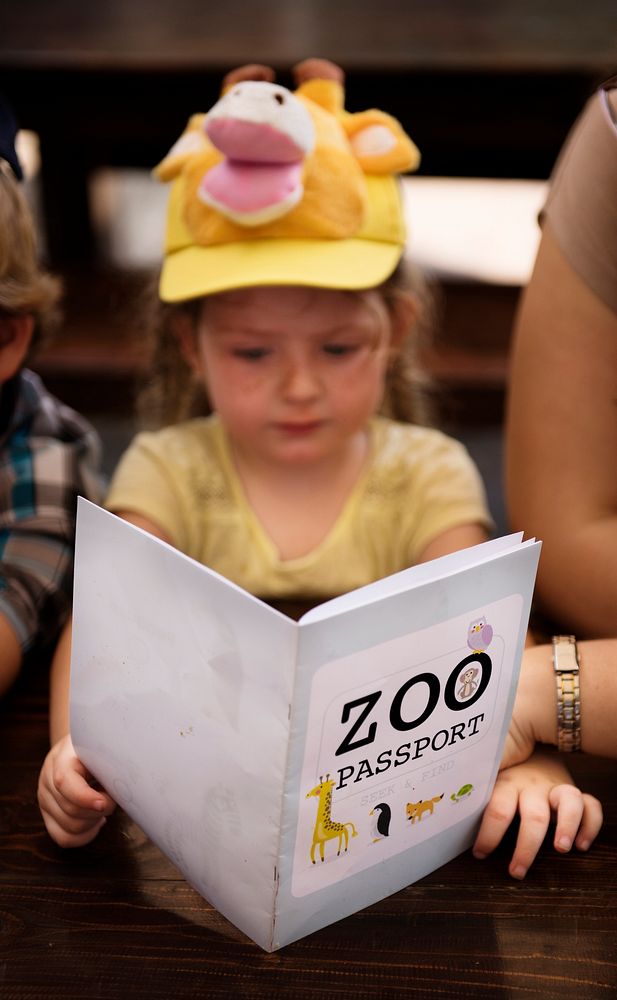 Caucasian girl holding zoo passport activity book