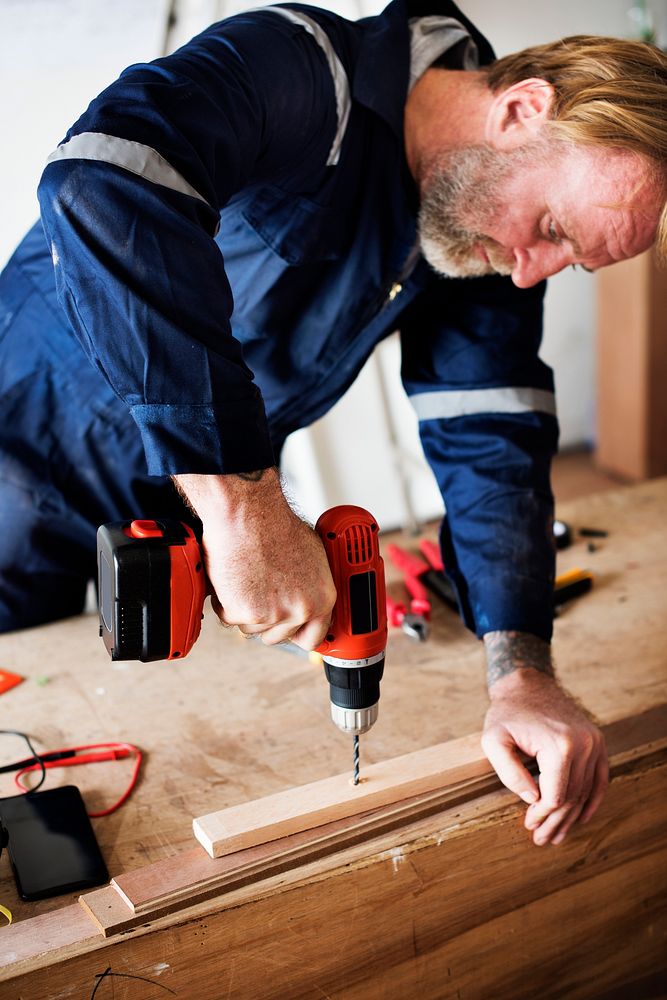 A carpenter using a drill on a wood