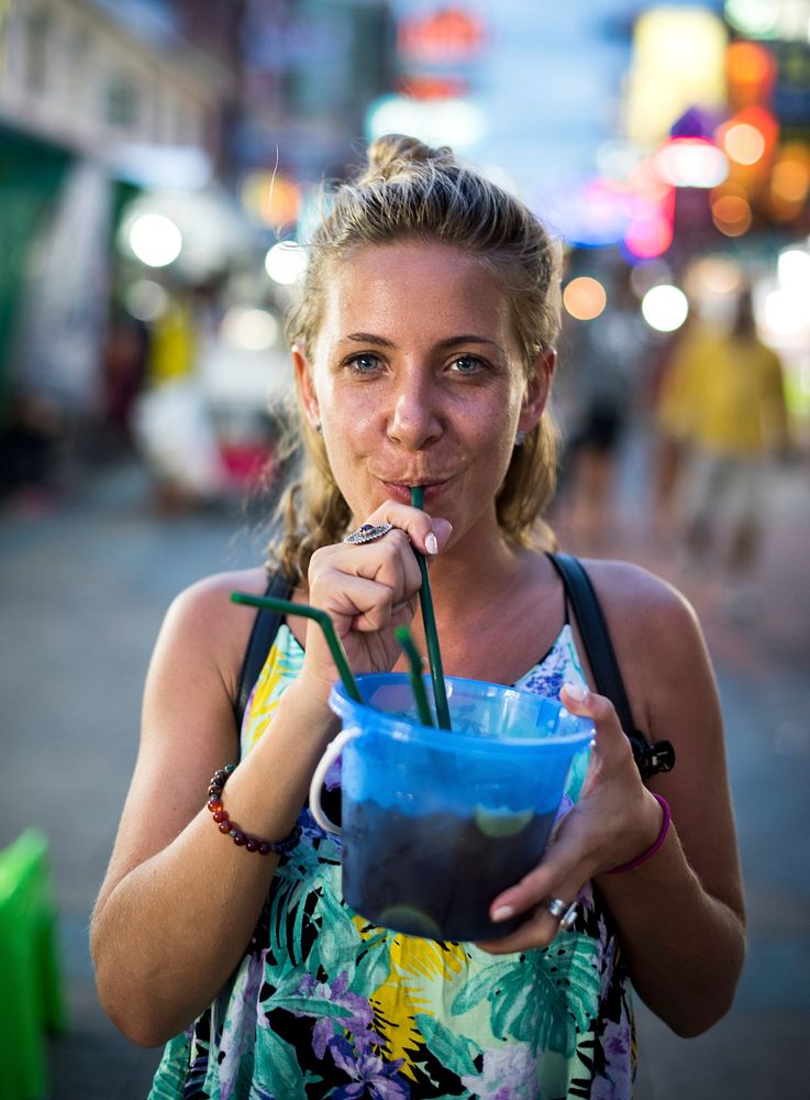 A female tourist enjoying bucket drink in Khao San Road , Bangkok, Thailand 