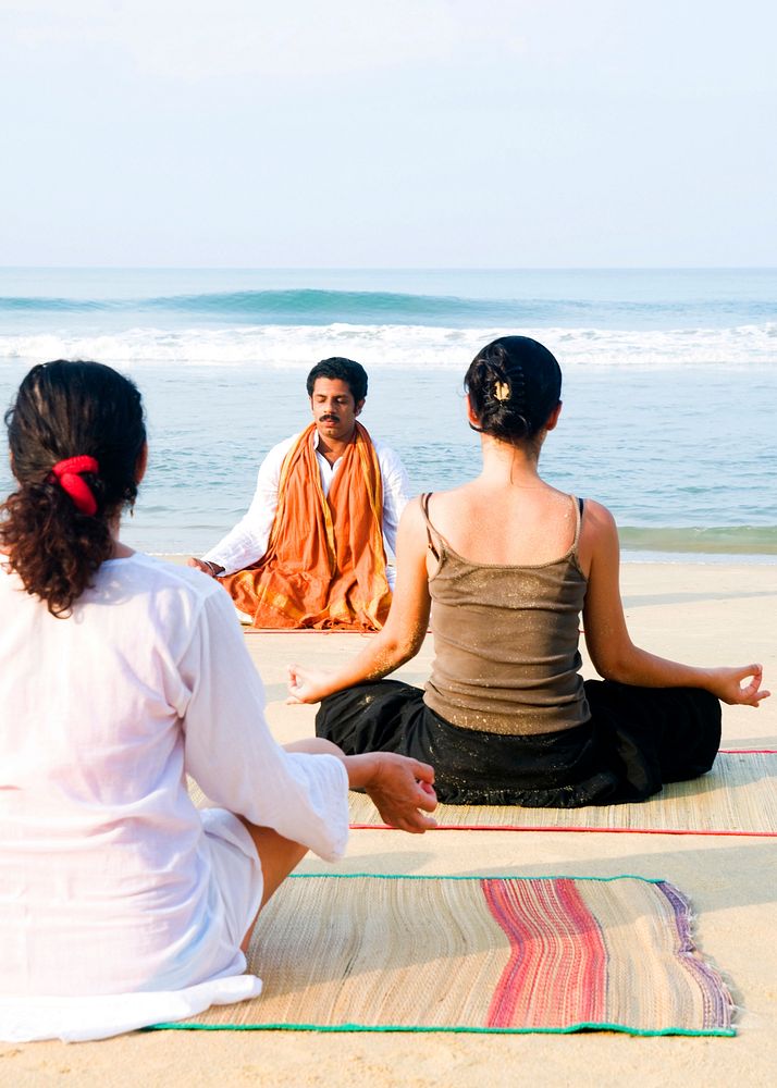 Yoga instructor and his students by the beach.
