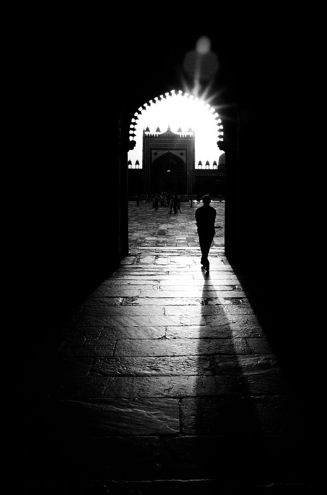 Silhouette of man walking through a mosque.