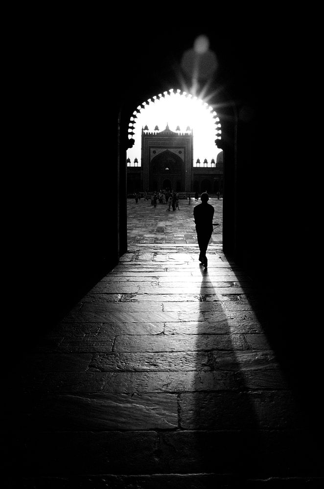 Silhouette of man walking through a mosque