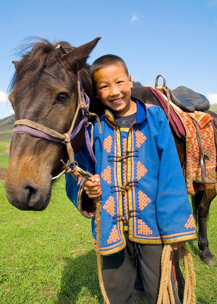 Little boy tilting his head to his horse and smiling at outdoors.