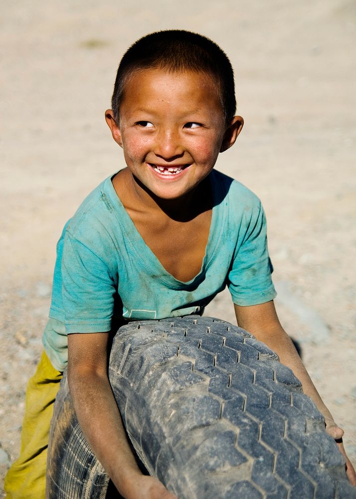 Asian boy with a beautiful smile playing with a tyre.