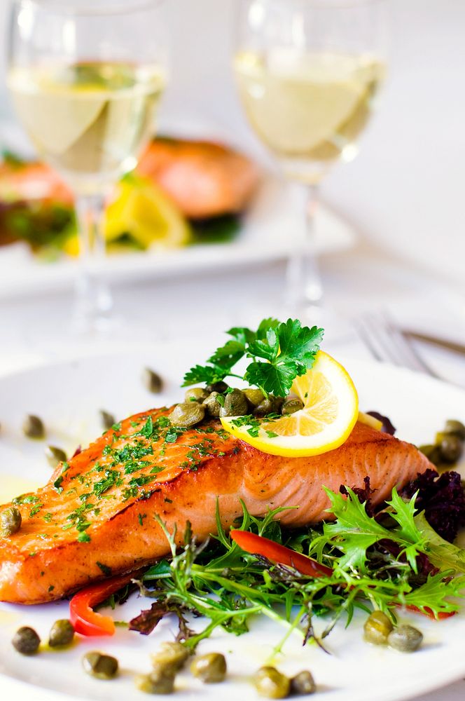 Grilled salmon fillet with vegetables and a glass of white wine.