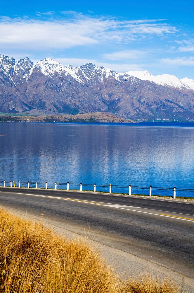 Asphalt road with lake and mountain range at the background.