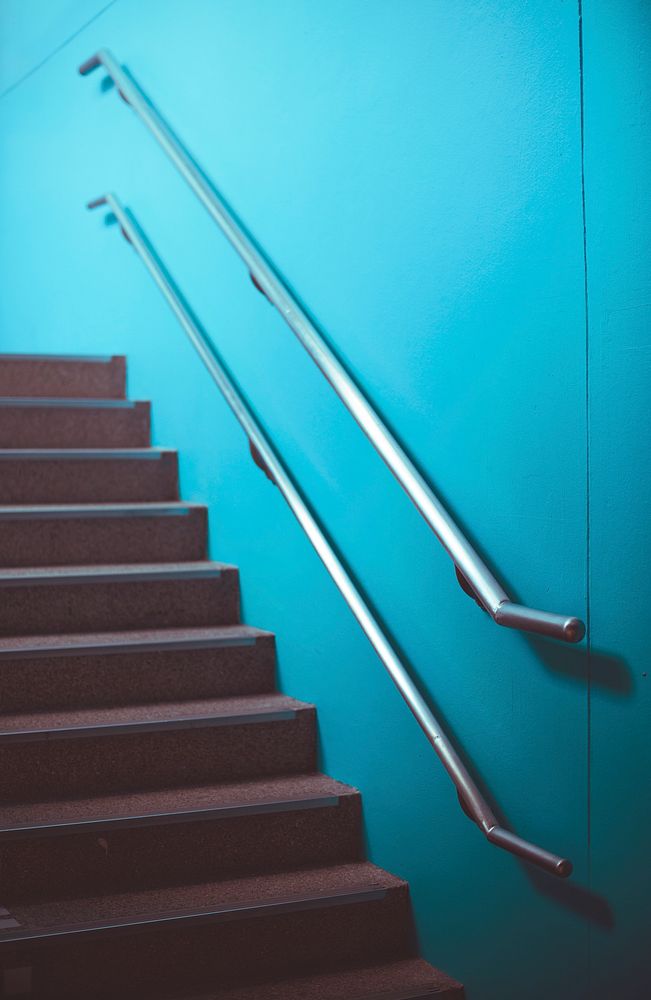 Staircase with stainless handrail on blue wall
